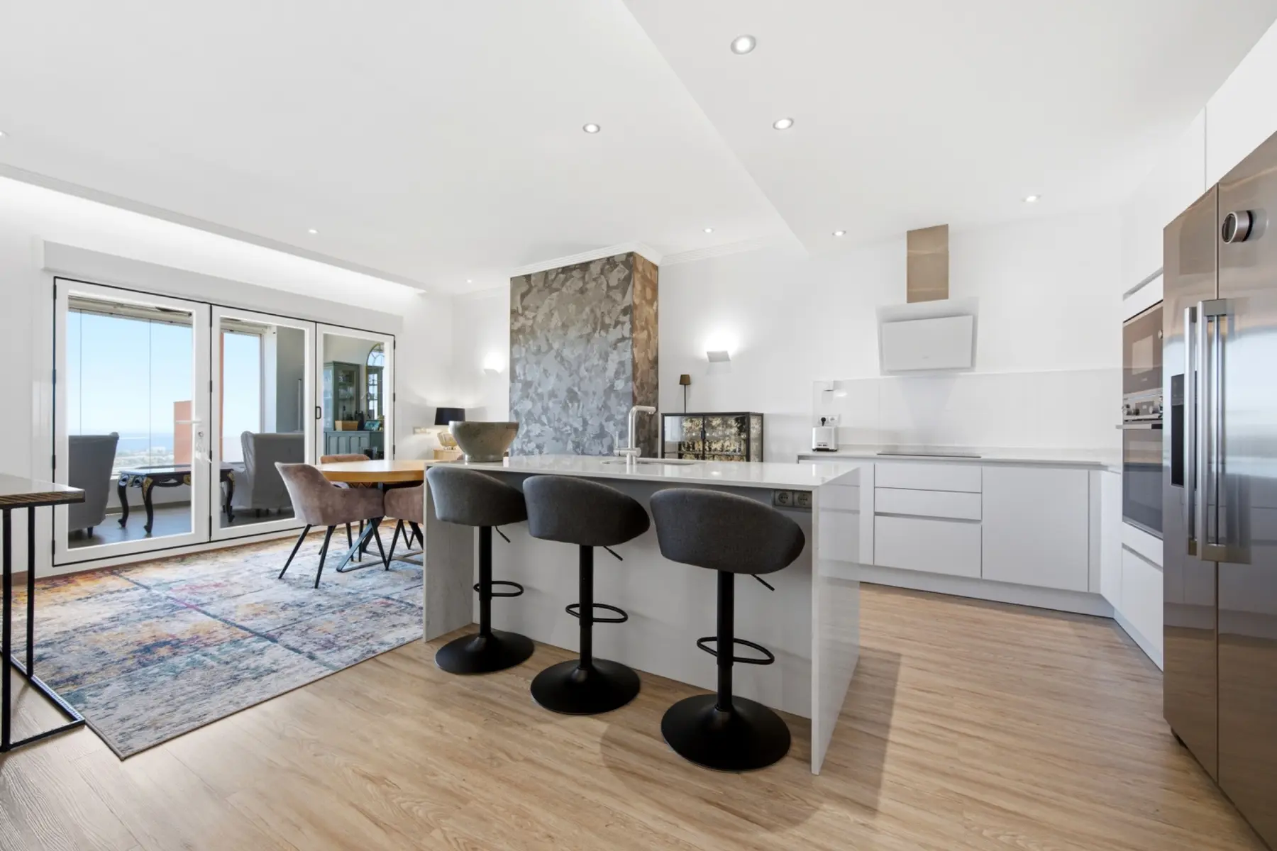 Cocina blanca abierta y comedor fotografiados en una vivienda de Benahavís
