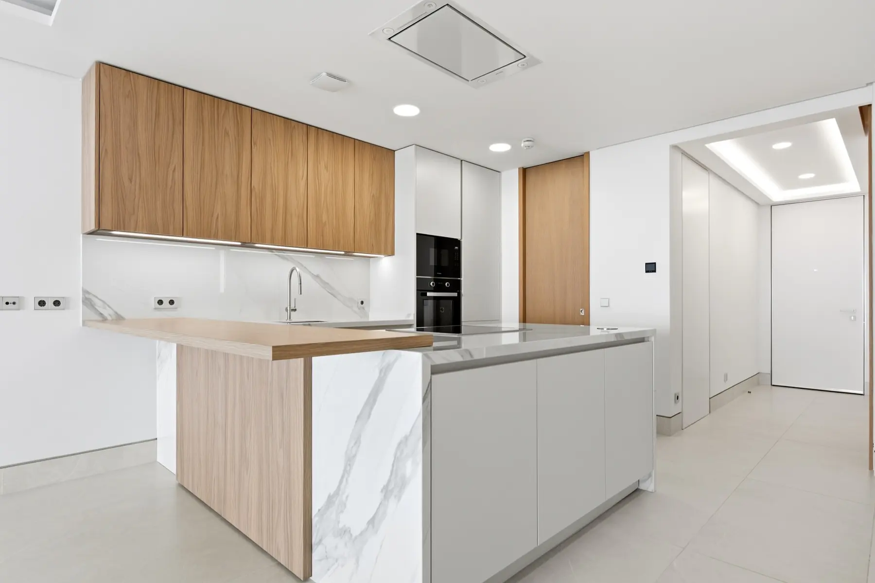 Cocina moderna con acabados blancos y madera fotografiada en Málaga