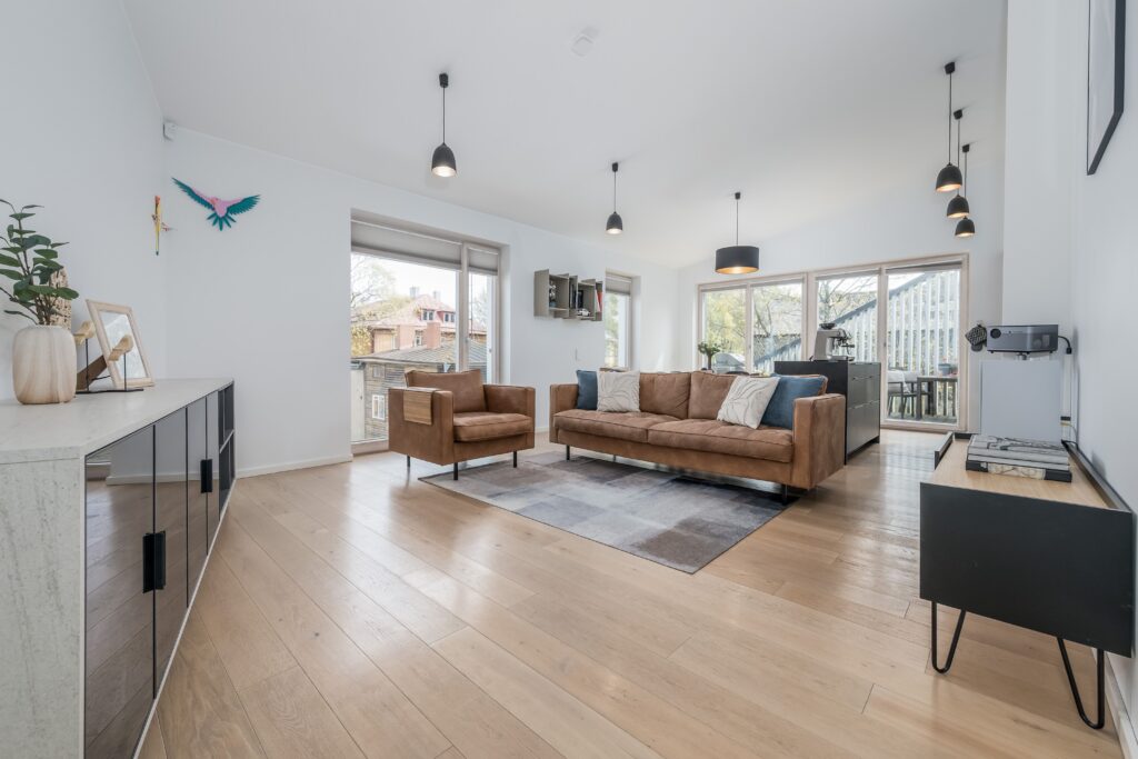 Salón moderno y luminoso con sofá de cuero, grandes ventanales y distribución abierta