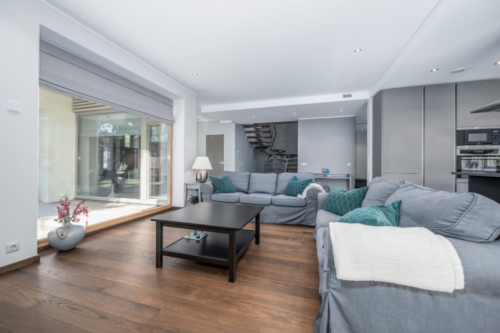 Fotografía inmobiliaria de salón moderno y luminoso con cocina abierta y terraza acristalada