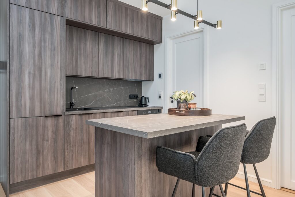 Fotografía inmobiliaria de cocina moderna con isla y taburetes, utilizada para anuncios de viviendas y marketing inmobiliario