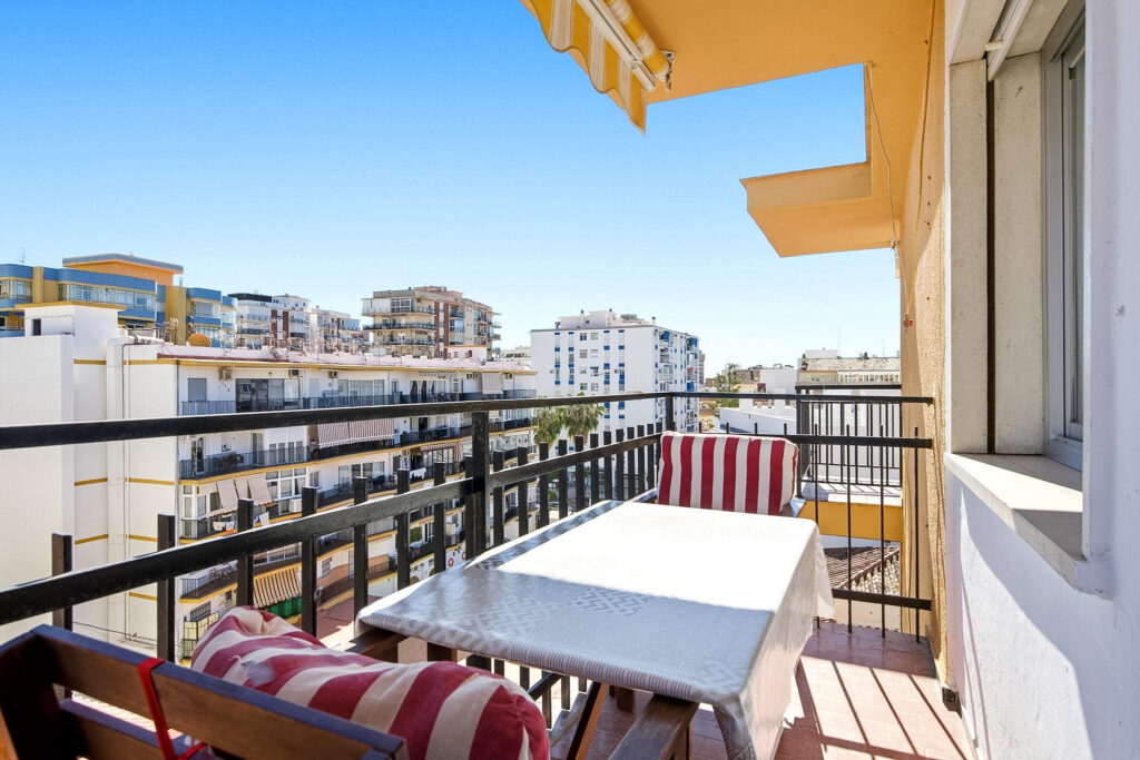 Fotografía inmobiliaria en Fuengirola – terraza con mesa y sillas, vistas urbanas y luz solar, Costa del Sol